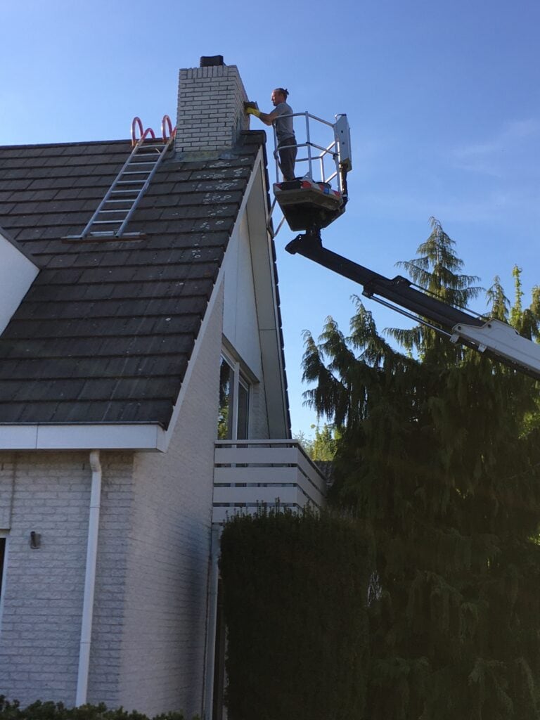 Vakman controleert vanuit een hoogwerker of het om een veilige schoorsteen gaat