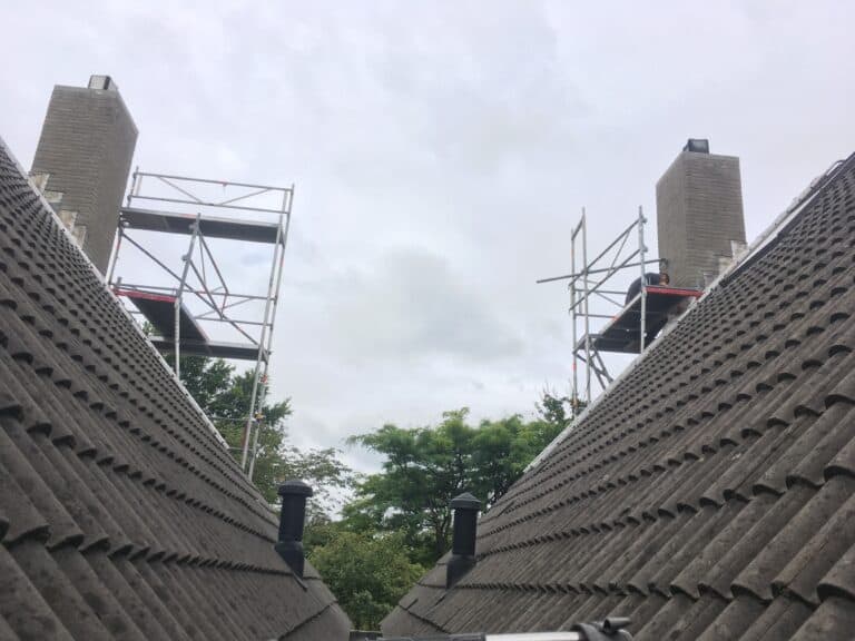 Steigers rondom twee schoorstenen tijdens werk aan een veilige schoorsteen
